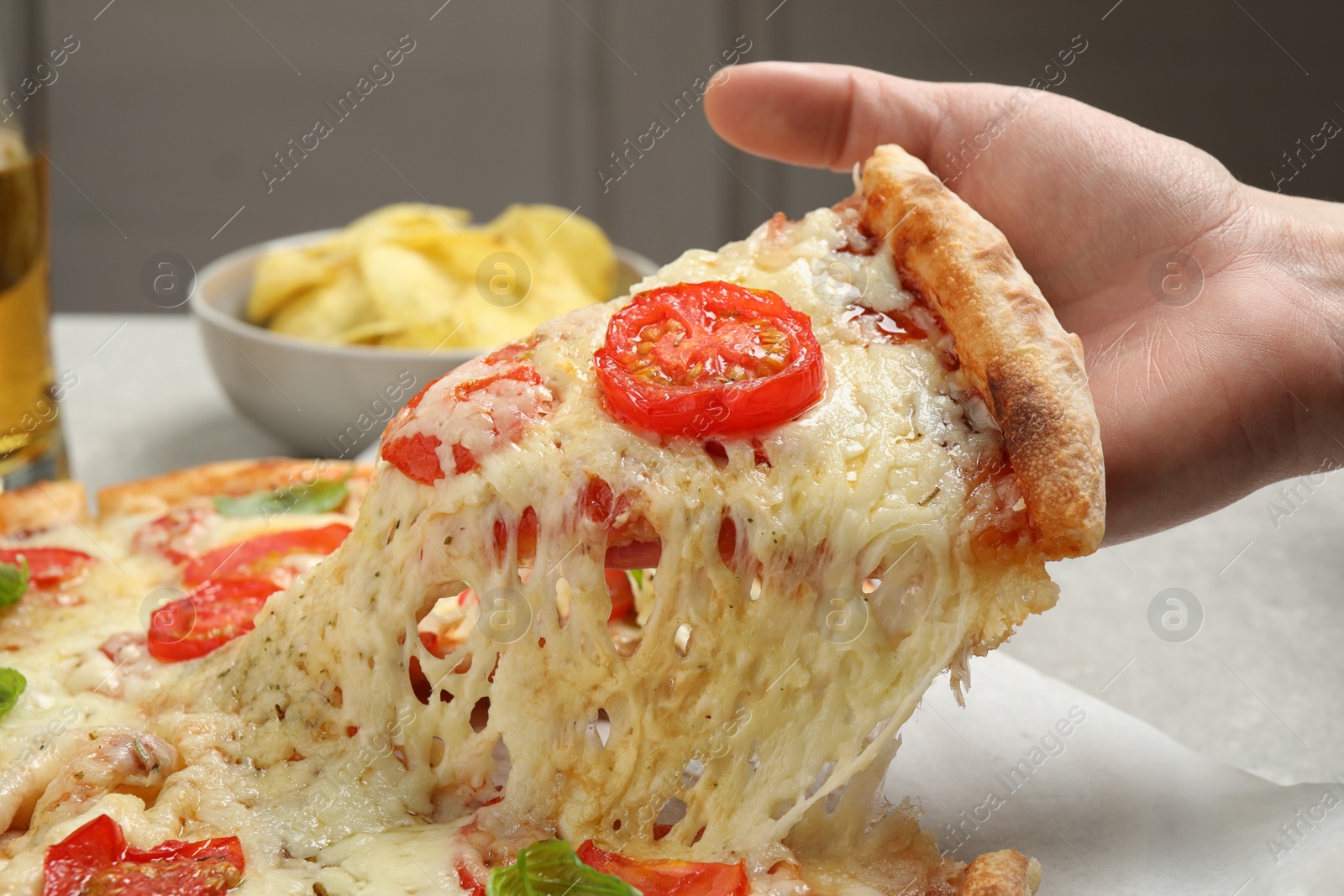 Photo of Woman taking slice of delicious pizza Margherita at table, closeup