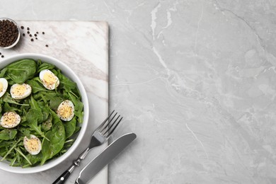 Photo of Delicious salad with boiled eggs and herbs served on light grey marble table, top view. Space for text