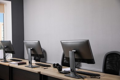 Open office interior. Modern workplaces with computers near light grey wall