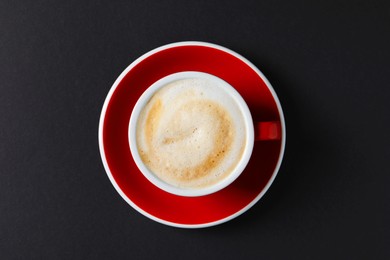 Photo of Cup with aromatic cappuccino on black background, top view