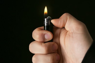 Photo of Man holding lighter on black background, closeup