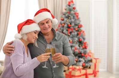 Happy mature couple with glasses of champagne at home. Christmas celebration