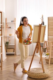 Photo of Beautiful young woman listening to music while drawing at home