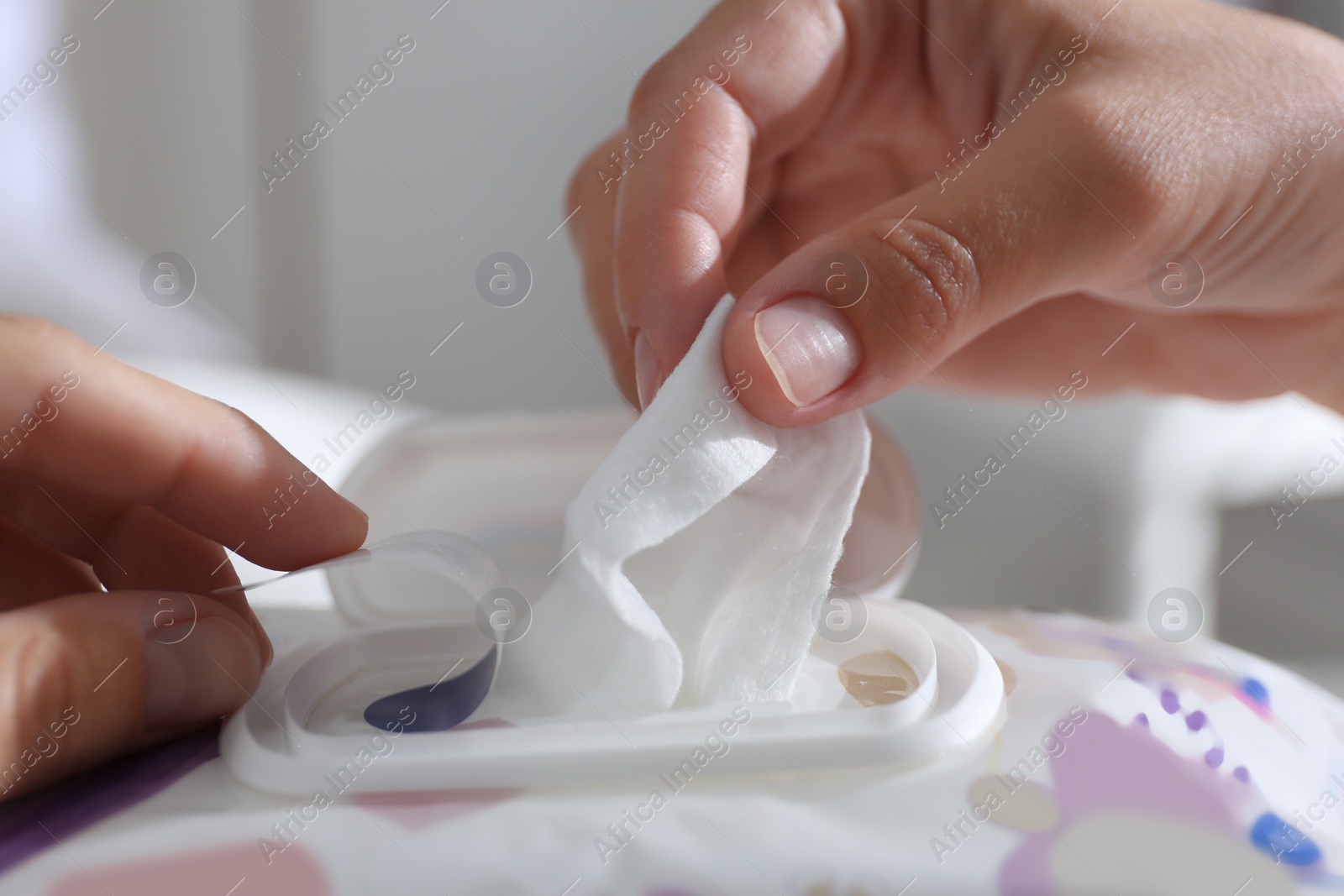 Photo of Woman taking wet wipe out of pack against blurred background, closeup