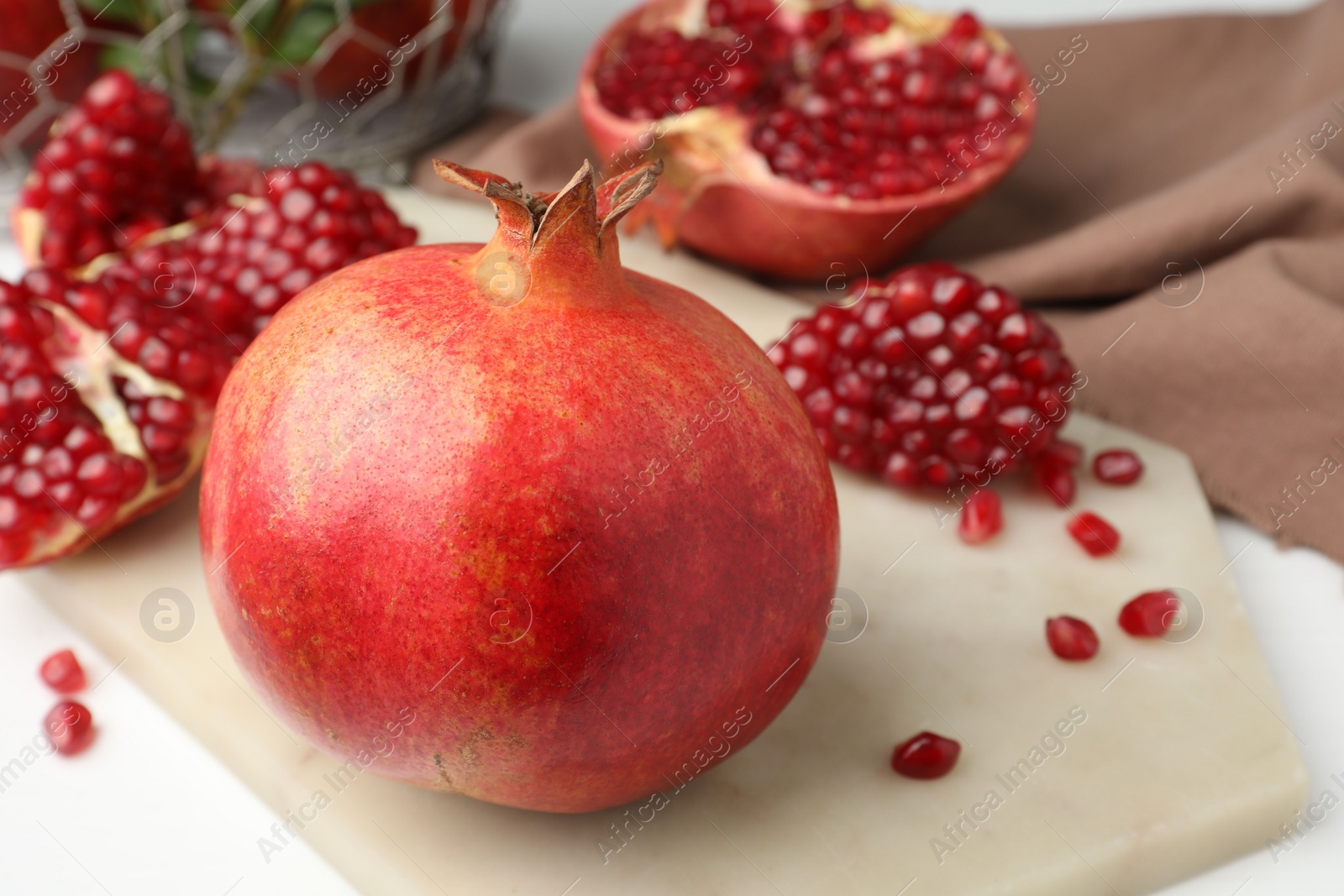 Photo of Fresh pomegranate and seeds on white table, closeup