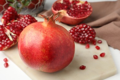 Photo of Fresh pomegranate and seeds on white table, closeup