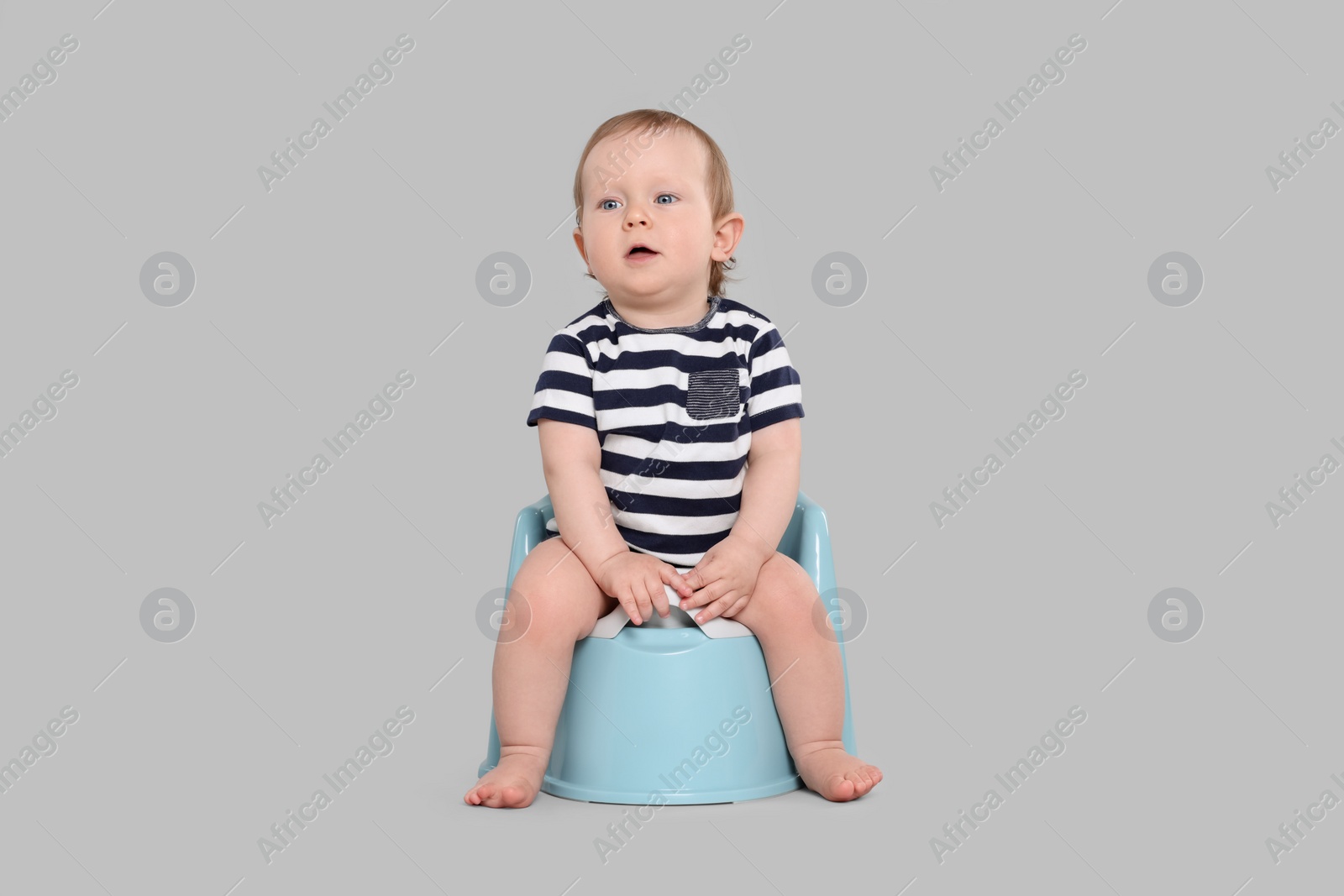 Photo of Little child sitting on baby potty against light grey background