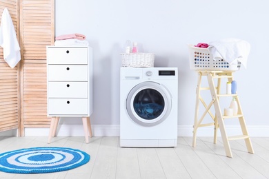 Photo of Washing machine with towels in laundry room interior