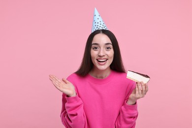 Photo of Woman in party hat with piece of tasty cake on pink background