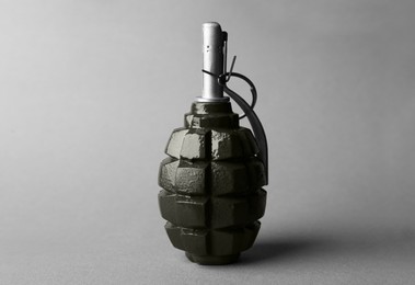 Hand grenade on grey background, closeup. Explosive weapon
