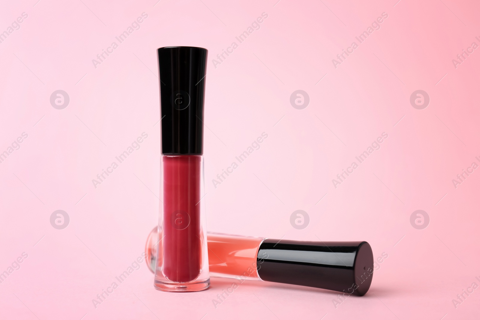 Photo of Beautiful lip glosses on color background