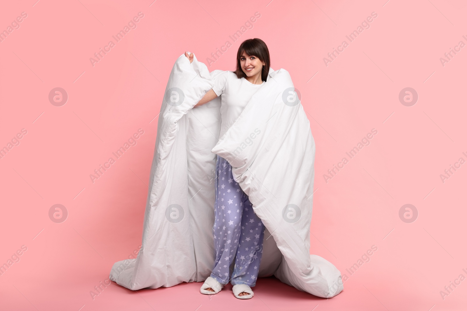 Photo of Happy woman in pyjama wrapped in blanket on pink background