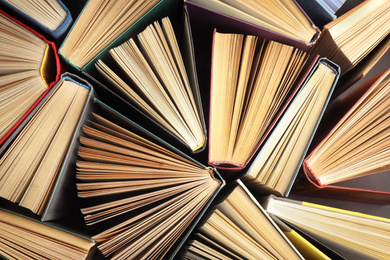 Photo of Many different hardcover books on dark background, top view