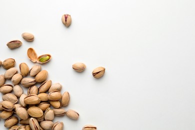 Photo of Pile of pistachio nuts on white background, flat lay. Space for text