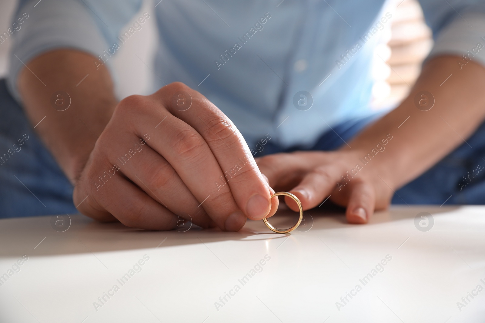 Photo of Man with wedding ring at table indoors, closeup. Divorce concept