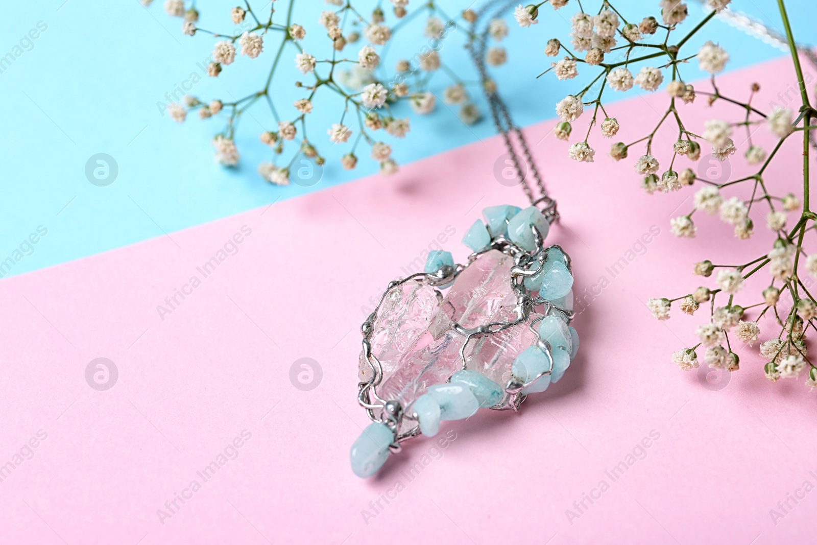 Photo of Beautiful silver pendent with pure quartz gemstones and flowers on color background