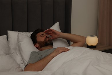 Photo of Man suffering from headache in bed at night
