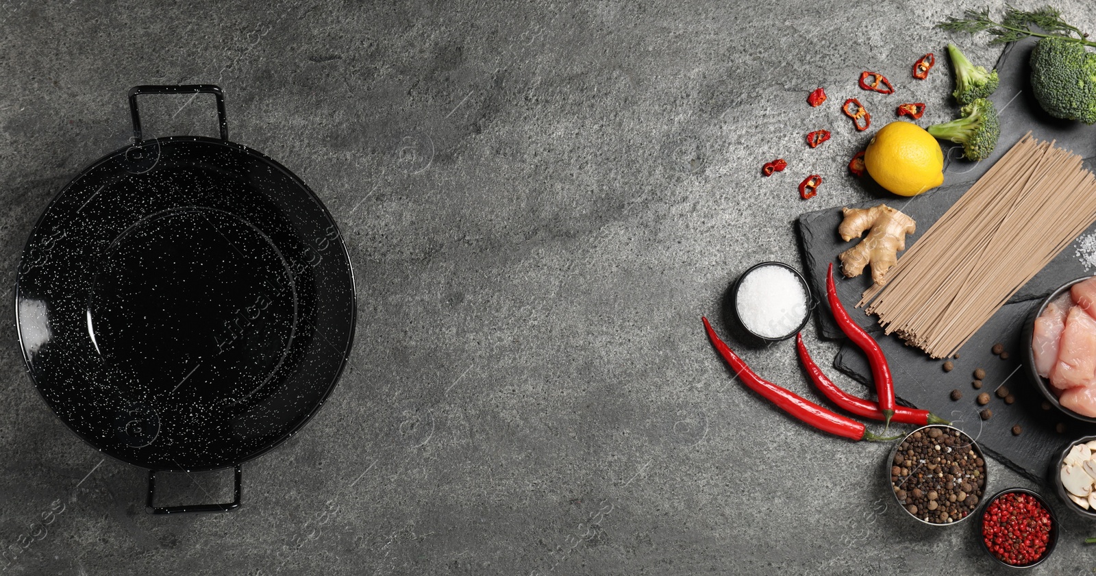 Photo of Empty iron wok and raw ingredients on grey table, flat lay. Space for text