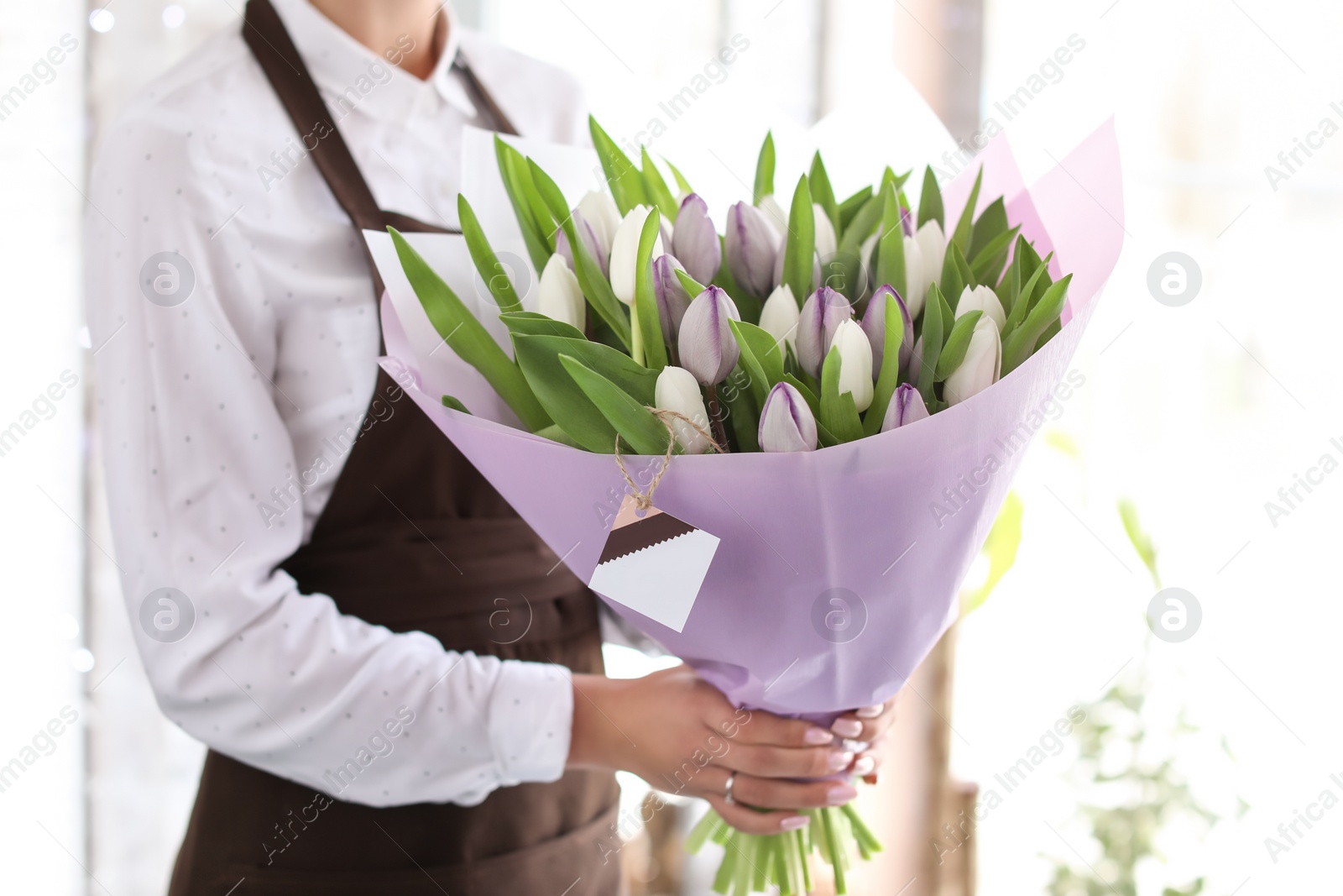 Photo of Female florist holding bouquet of beautiful flowers in shop