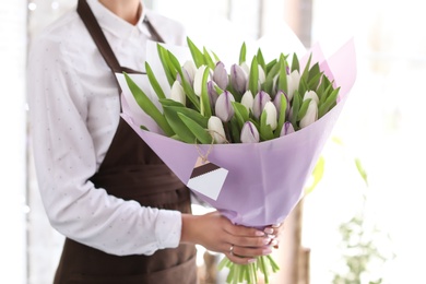 Photo of Female florist holding bouquet of beautiful flowers in shop