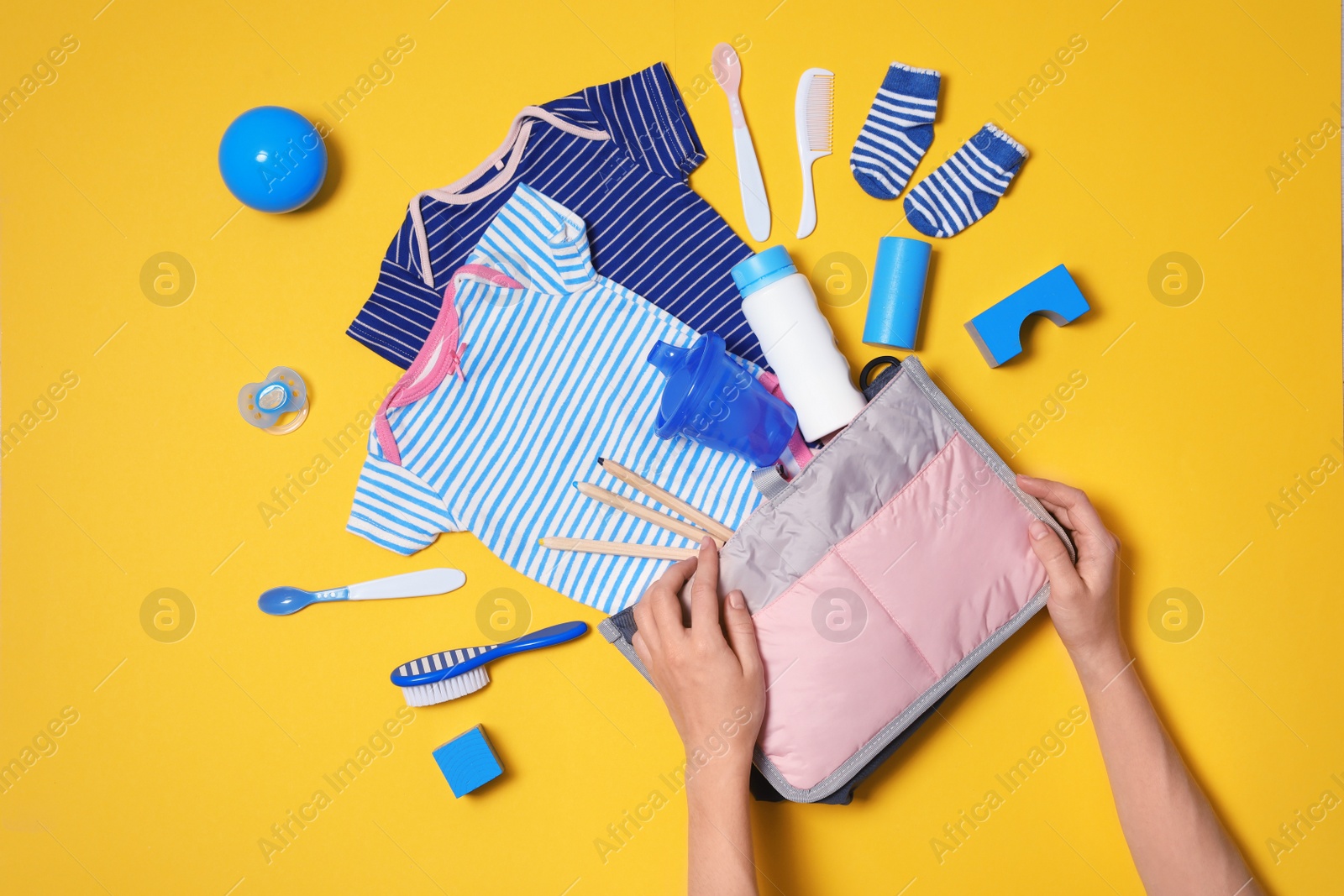 Photo of Woman with maternity bag and baby accessories on color background, top view