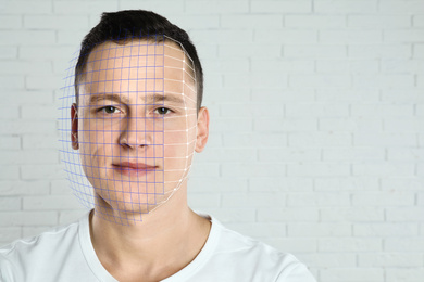 Image of Facial recognition system. Man with digital biometric grid against brick wall