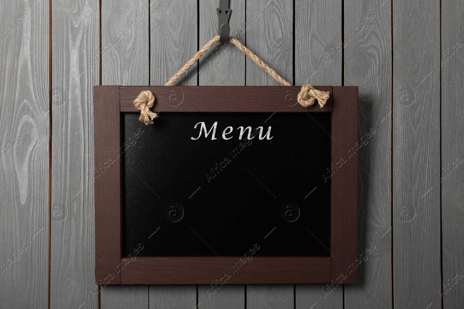 Image of Black chalkboard with word Menu hanging on grey wooden wall. Mockup for design