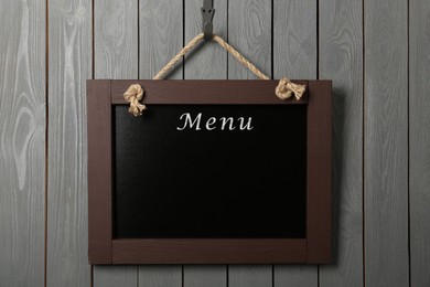 Image of Black chalkboard with word Menu hanging on grey wooden wall. Mockup for design