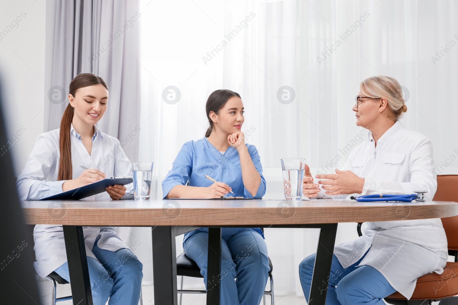 Photo of Medical conference. Doctors listening to speaker at wooden table in office