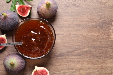 Photo of Glass bowl with tasty sweet jam and fresh figs on wooden table, flat lay. Space for text