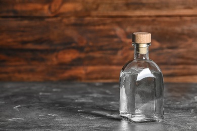 Glass bottle with vinegar on wooden background. Space for text