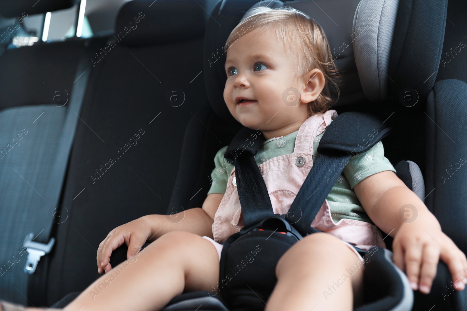 Photo of Cute little girl sitting in child safety seat inside car