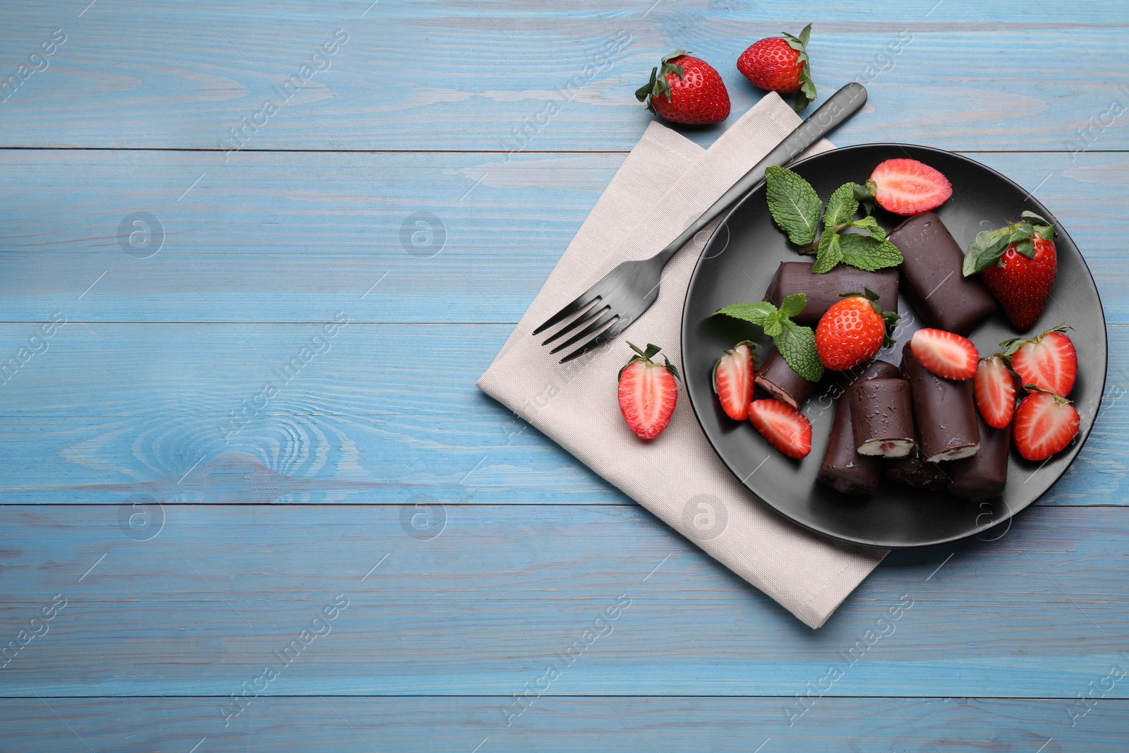 Photo of Delicious glazed curd snacks with fresh strawberries and mint on light blue wooden table, flat lay. Space for text