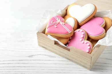 Photo of Decorated heart shaped cookies in wooden box on table. Space for text