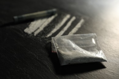 Photo of Drug addiction. Plastic bag with cocaine and rolled dollar banknote on grey textured table, selective focus