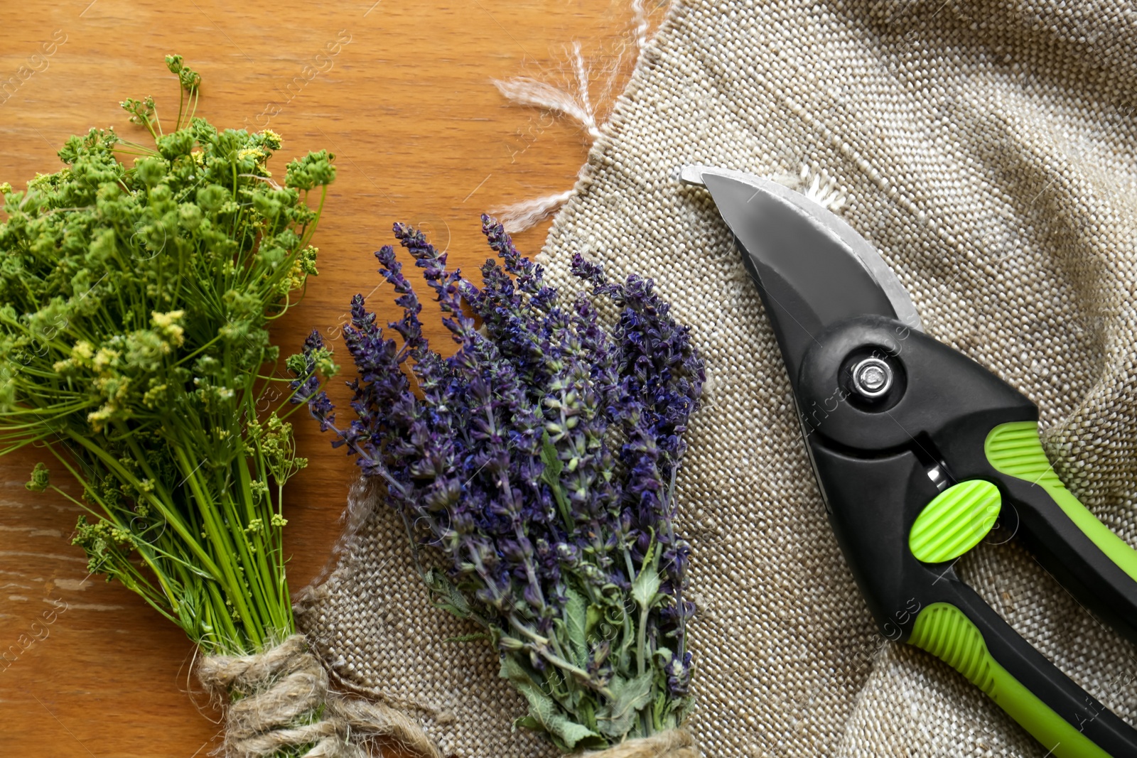 Photo of Secateur, lavender and wild flowers on wooden table, flat lay