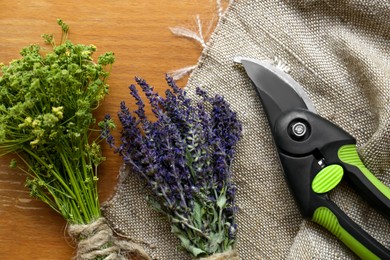 Photo of Secateur, lavender and wild flowers on wooden table, flat lay