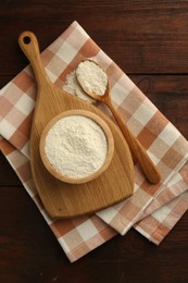 Photo of Baking powder in bowl and spoon on wooden table, top view