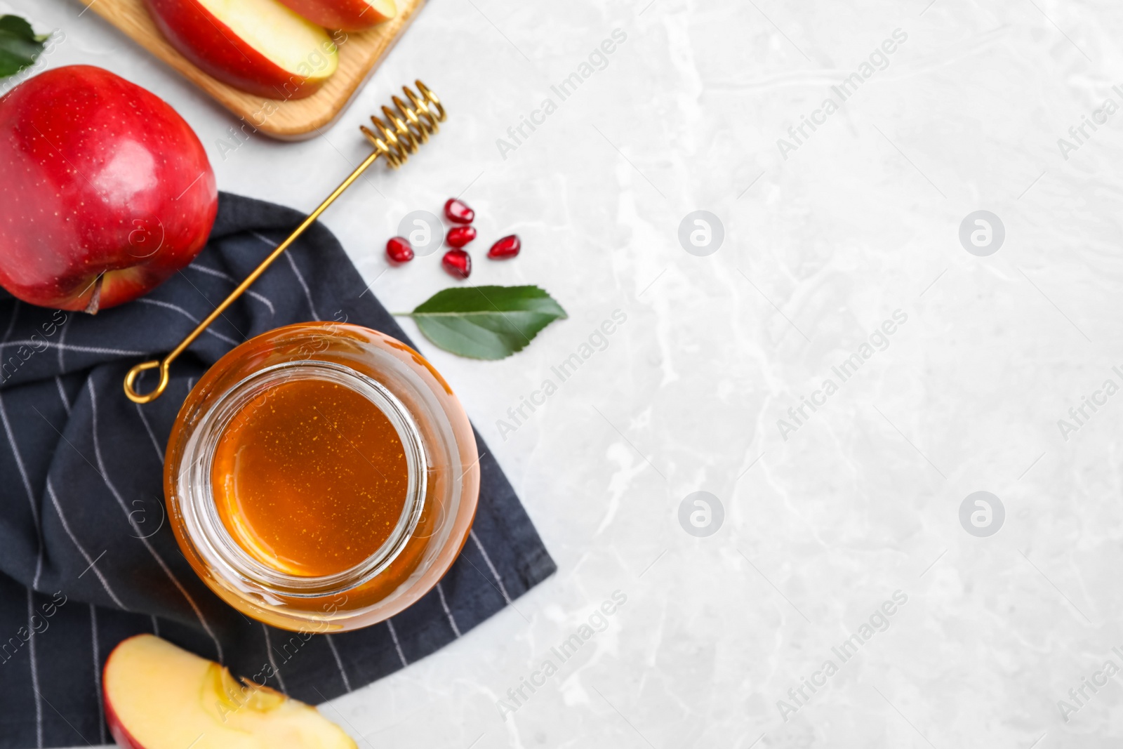 Photo of Honey, apples and pomegranate seeds on light grey marble table, flat lay with space for text. Rosh Hashanah holiday