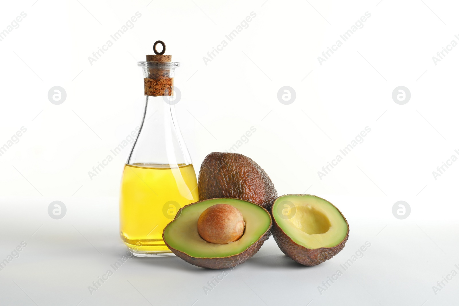 Photo of Bottle with oil and ripe fresh avocados on white background