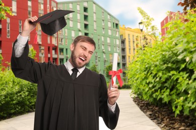 Image of Happy student with graduation hat and diploma outdoors
