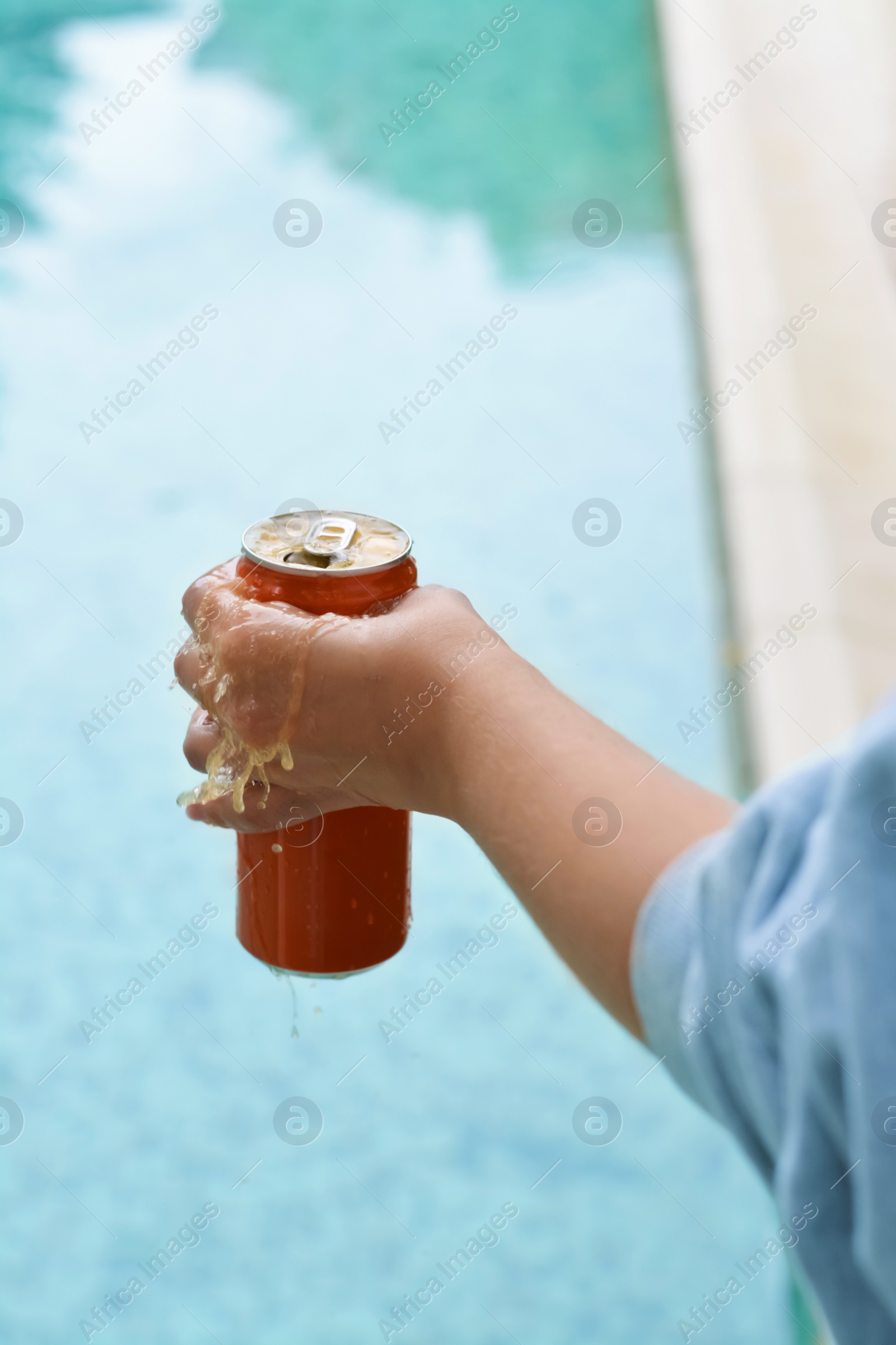 Photo of Woman holding tasty open canned beverage near swimming pool, closeup