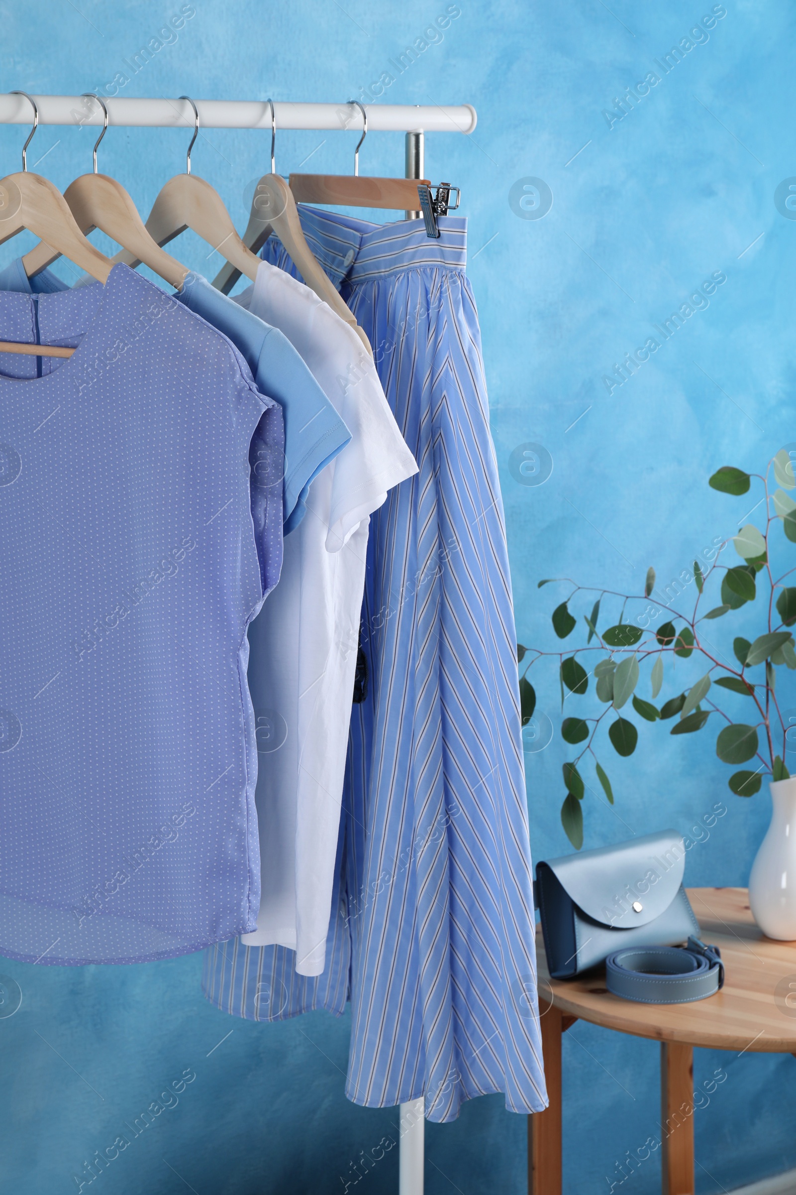 Photo of Rack with stylish clothes near light blue wall indoors