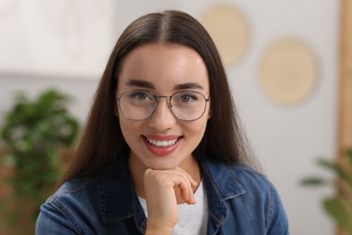 Photo of Portrait of beautiful young woman with glasses indoors. Attractive lady smiling and looking into camera