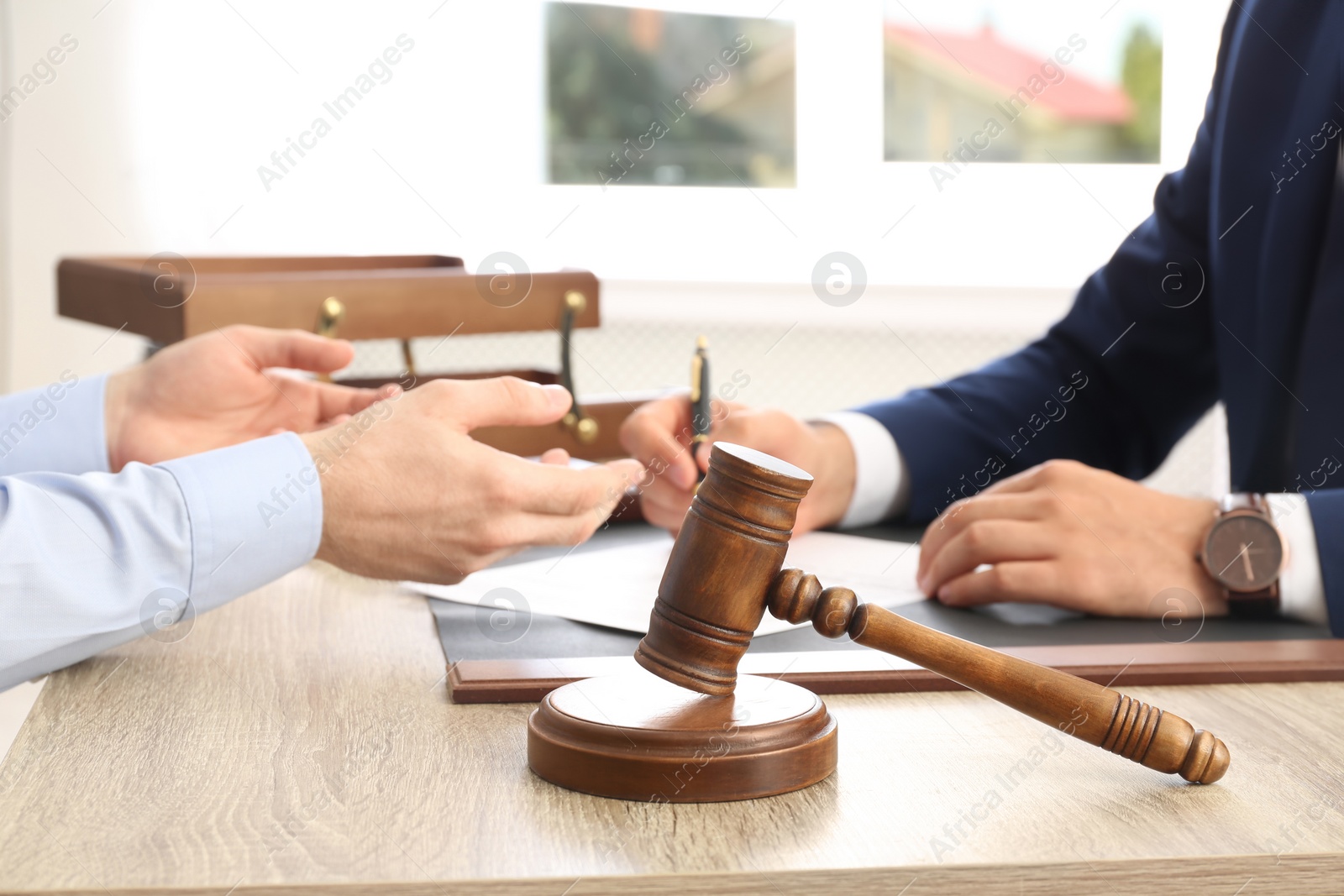 Photo of Gavel and blurred lawyer working with client on background