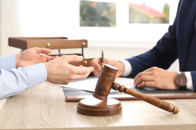 Photo of Gavel and blurred lawyer working with client on background
