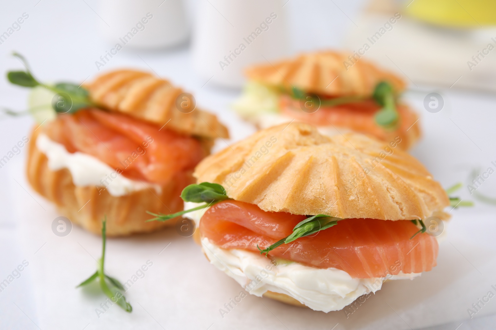 Photo of Delicious profiteroles with cream cheese and salmon on table, closeup