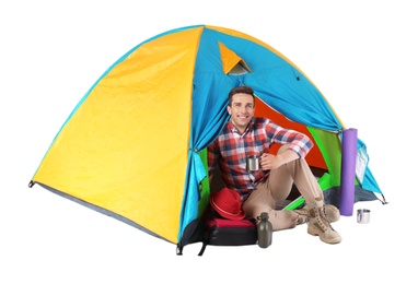 Photo of Young handsome man sitting in tourist tent on white background