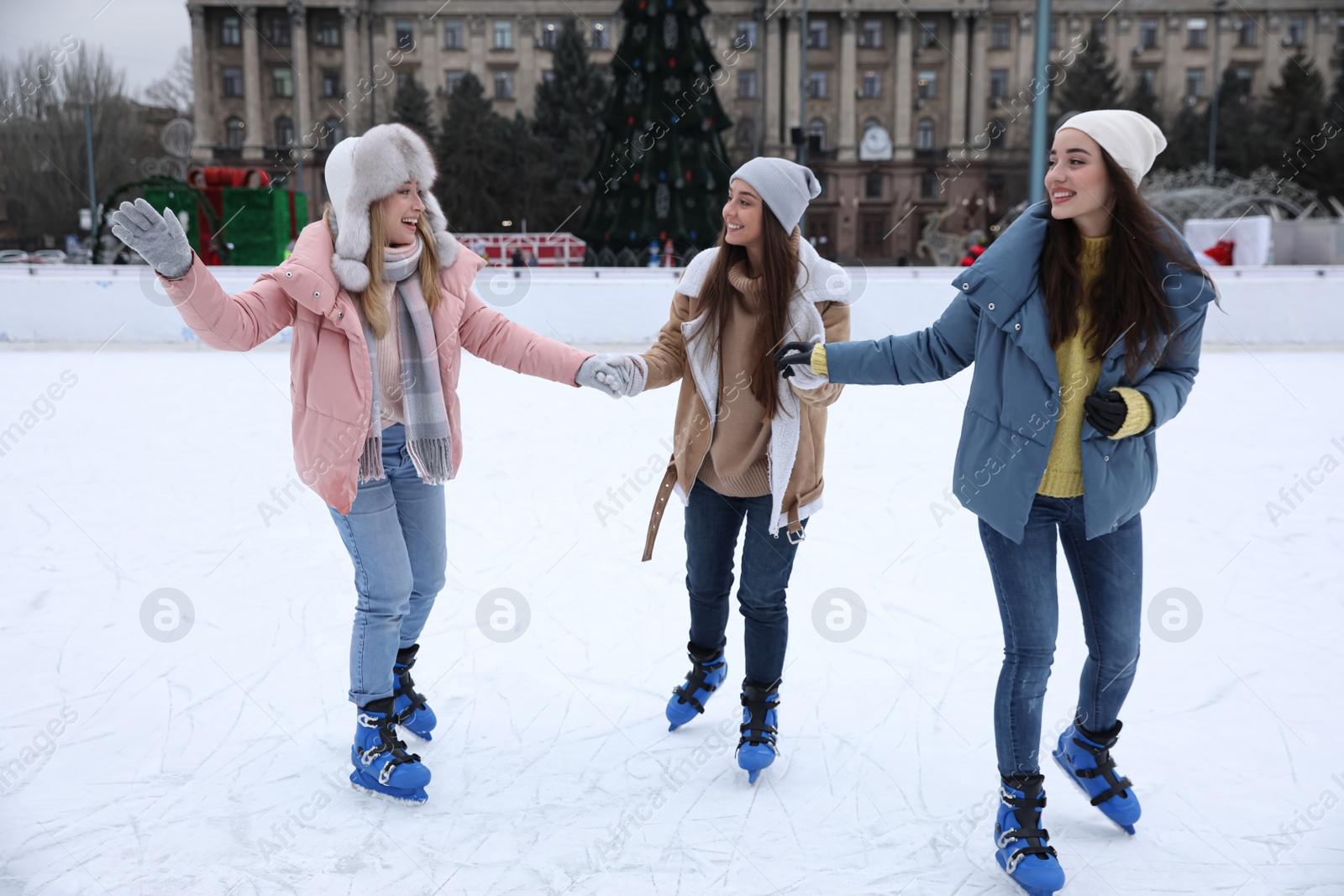 Image of Happy women skating along ice rink outdoors