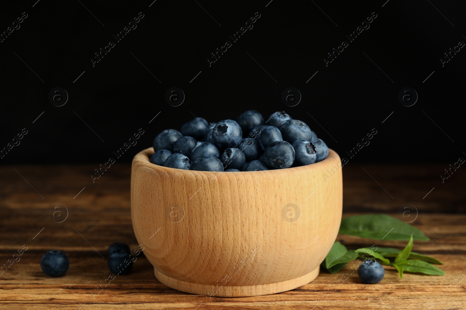 Photo of Fresh ripe blueberries in bowl on wooden table